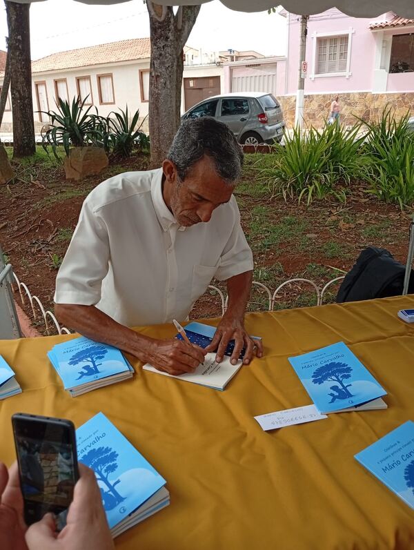 Autor autografando exemplares em sessão de lançamento