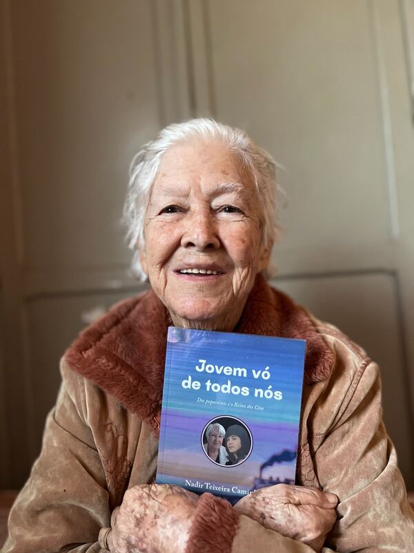 Autora sorridente segurando seu livro publicado